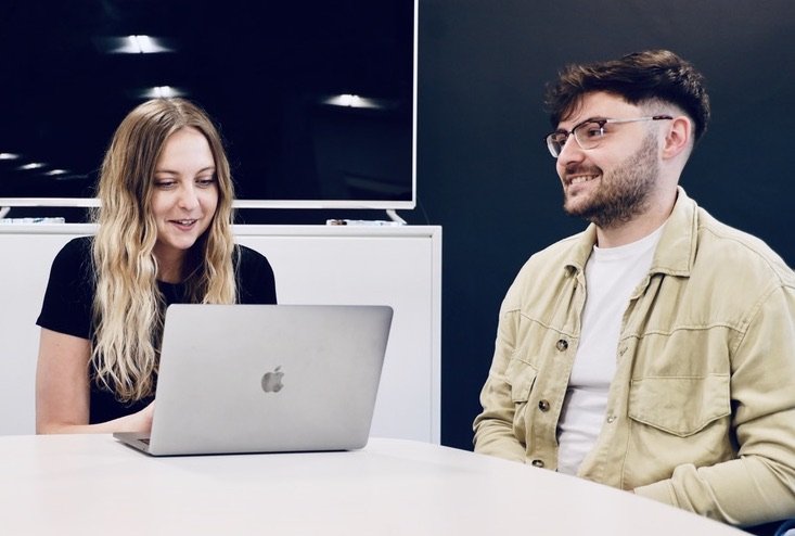 Two members of the Damteq team working from a Apple MacBook Pro laptop.