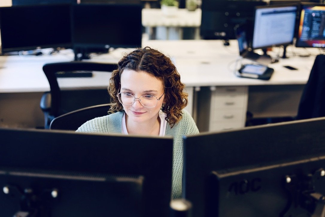 A User Experience Specialist working at her desk in a busy office.