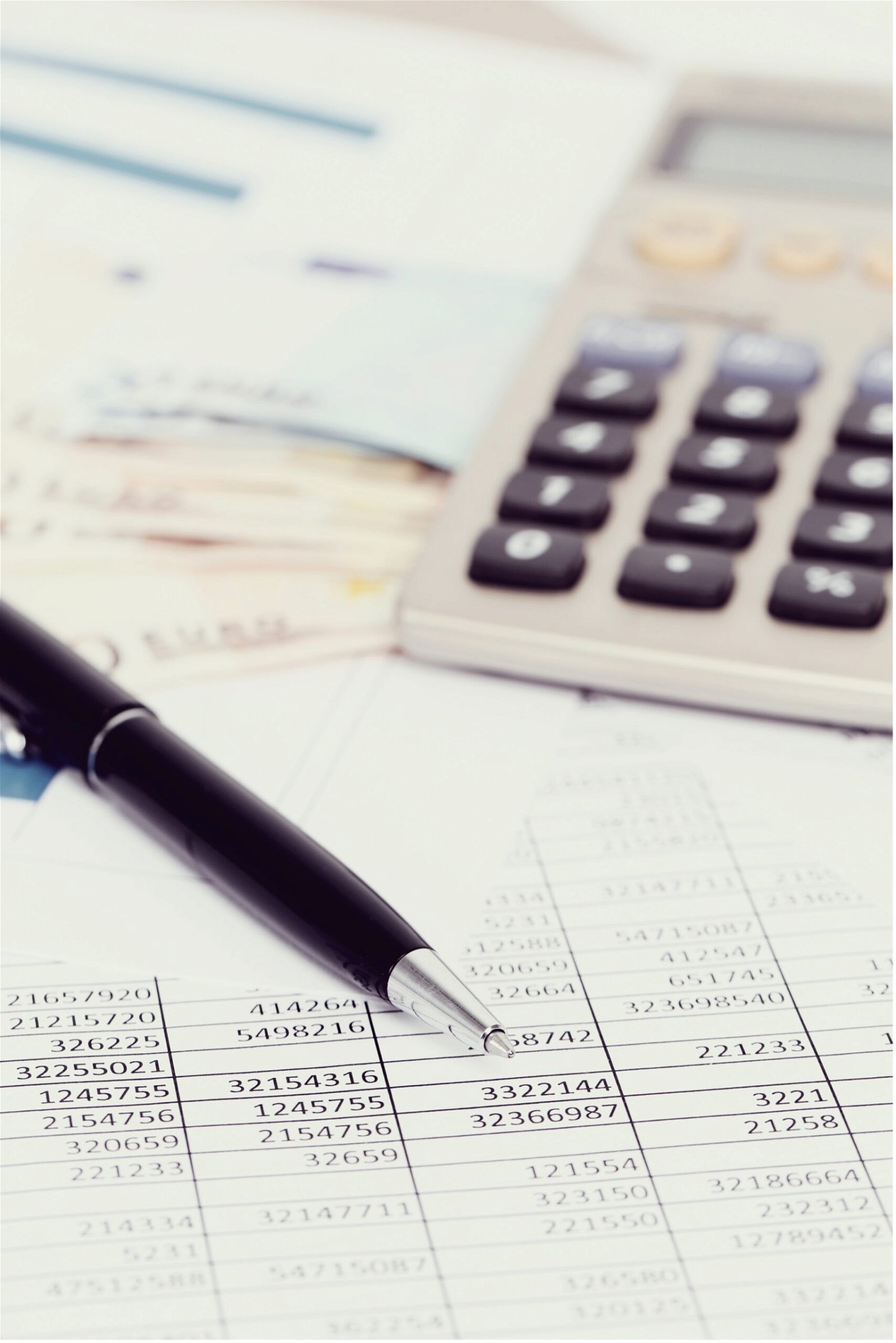 A closeup of a business' financial balance sheet with a pen and calculator resting on top.