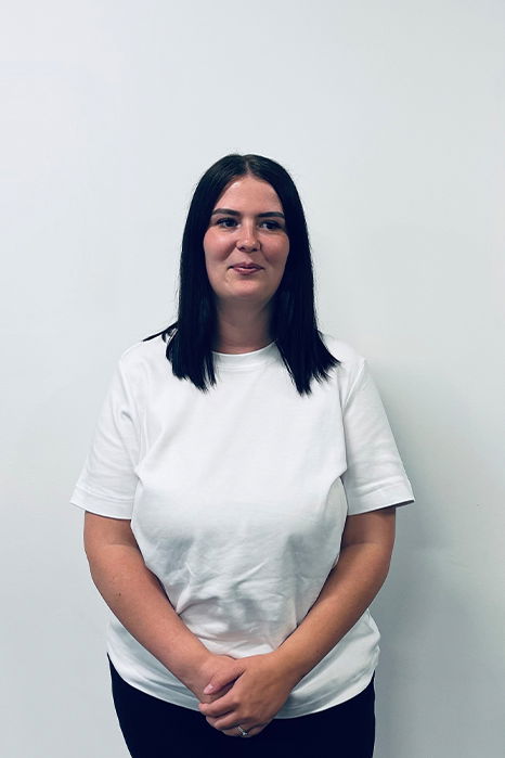 Ashleigh Old, one of Damteq's PPC Specialists stood in front of a white wall, looking straight forward while smiling at the camera.